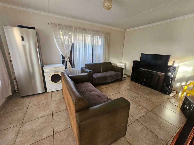 A living room featuring tiled flooring and coved ceilings, currently utilized as a multi-purpose living and utility space.