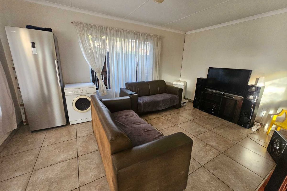 A living room featuring tiled flooring and coved ceilings, currently utilized as a multi-purpose living and utility space.