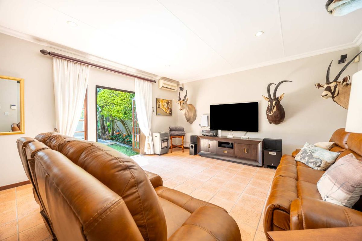 A comfortable living room featuring tiled flooring, recessed lighting, and direct access to the garden through double glass doors.