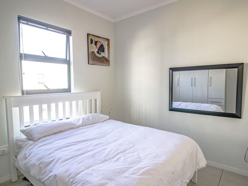 A functional bedroom featuring tiled flooring, a window for natural light, and built-in cupboards for storage.