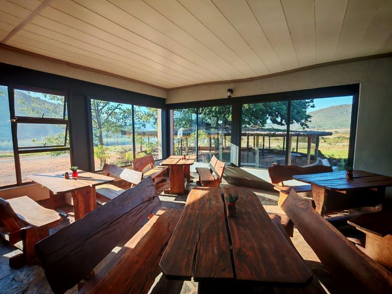 A bright, open-plan dining area featuring extensive glass walls that provide panoramic views of the surrounding landscape and outdoor patio space.