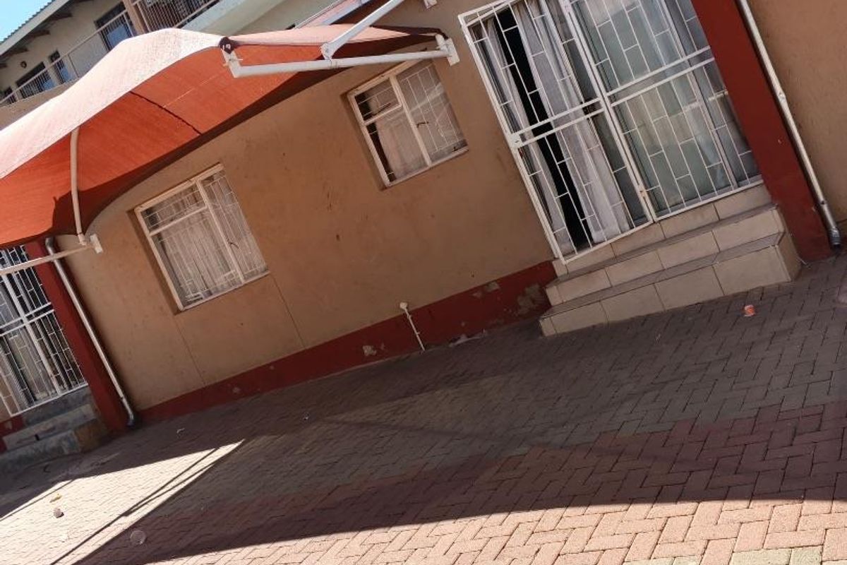 Rear courtyard area featuring paved flooring, shade sails for sun protection, and secure access points to the apartment building.