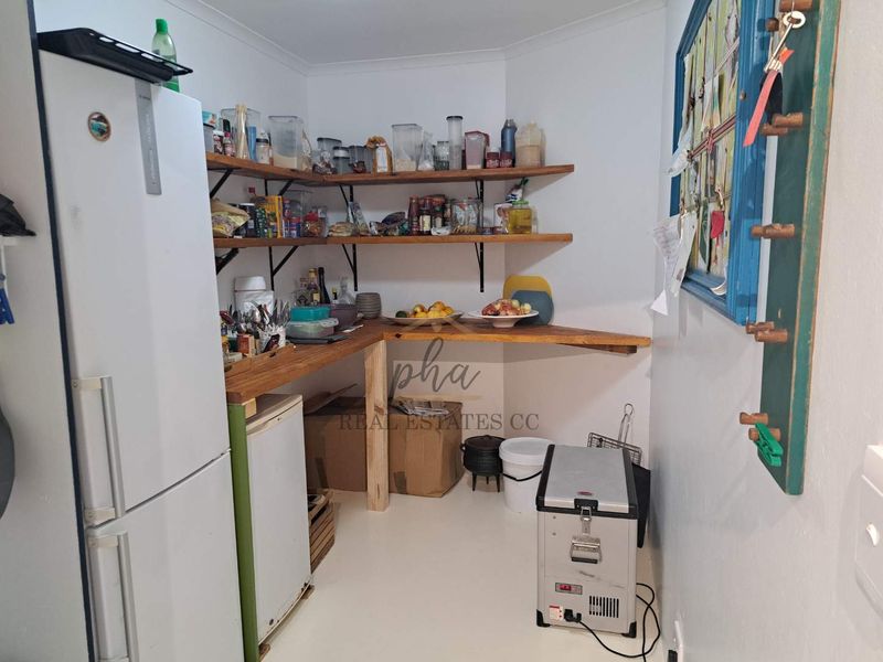A functional scullery or pantry area featuring open wooden shelving and a wooden countertop for additional storage and preparation space.