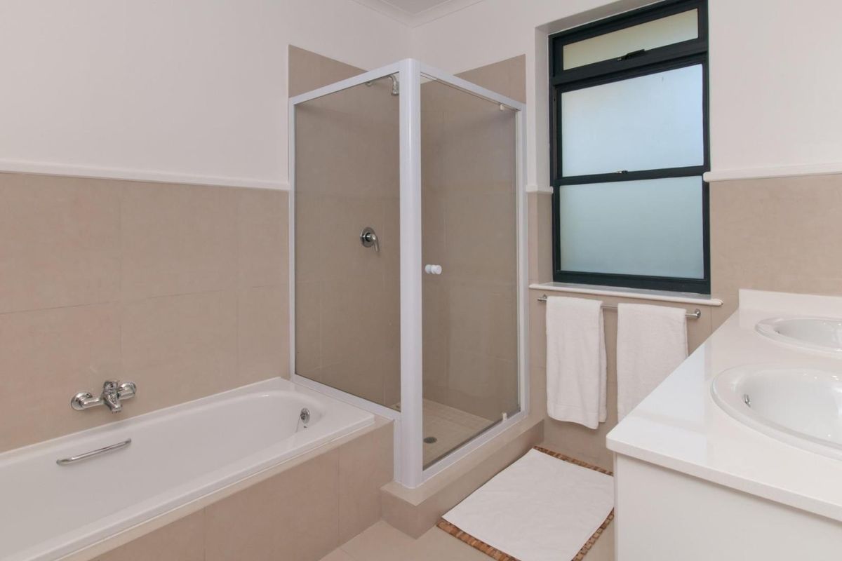 A clean, functional bathroom featuring a built-in bathtub, a separate glass-enclosed shower, and a double vanity with integrated sinks.