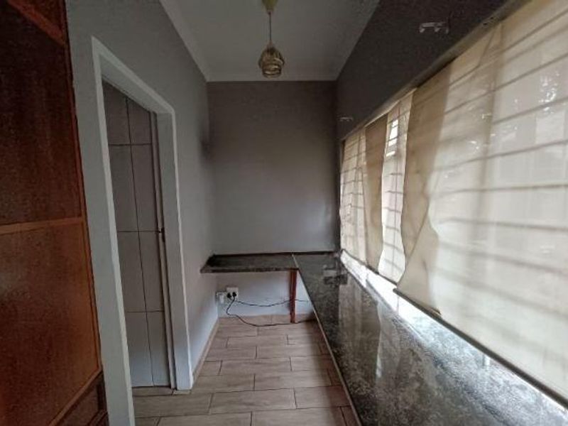 A functional scullery or utility area featuring granite countertops, tiled flooring, and built-in cabinetry, providing additional workspace and storage.