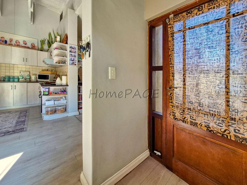 Entryway leading into an open-plan kitchen area featuring laminate flooring and timber-framed glass door access.