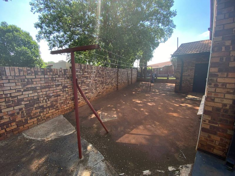 A rear courtyard area featuring face brick boundary walls, a paved surface, and a fixed washing line, providing a functional outdoor utility space.