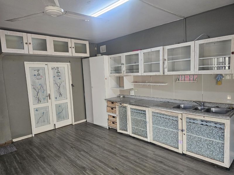 A functional kitchen space featuring built-in cabinetry, granite countertops, and a double basin sink, offering a blank canvas for modern renovation.