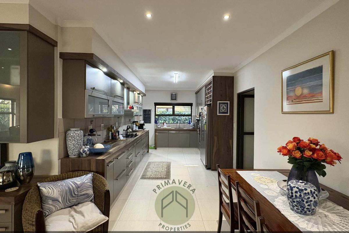 Modern galley-style kitchen featuring extensive built-in cabinetry, laminate countertops, tiled flooring, and integrated lighting, offering a functional and well-maintained culinary space.