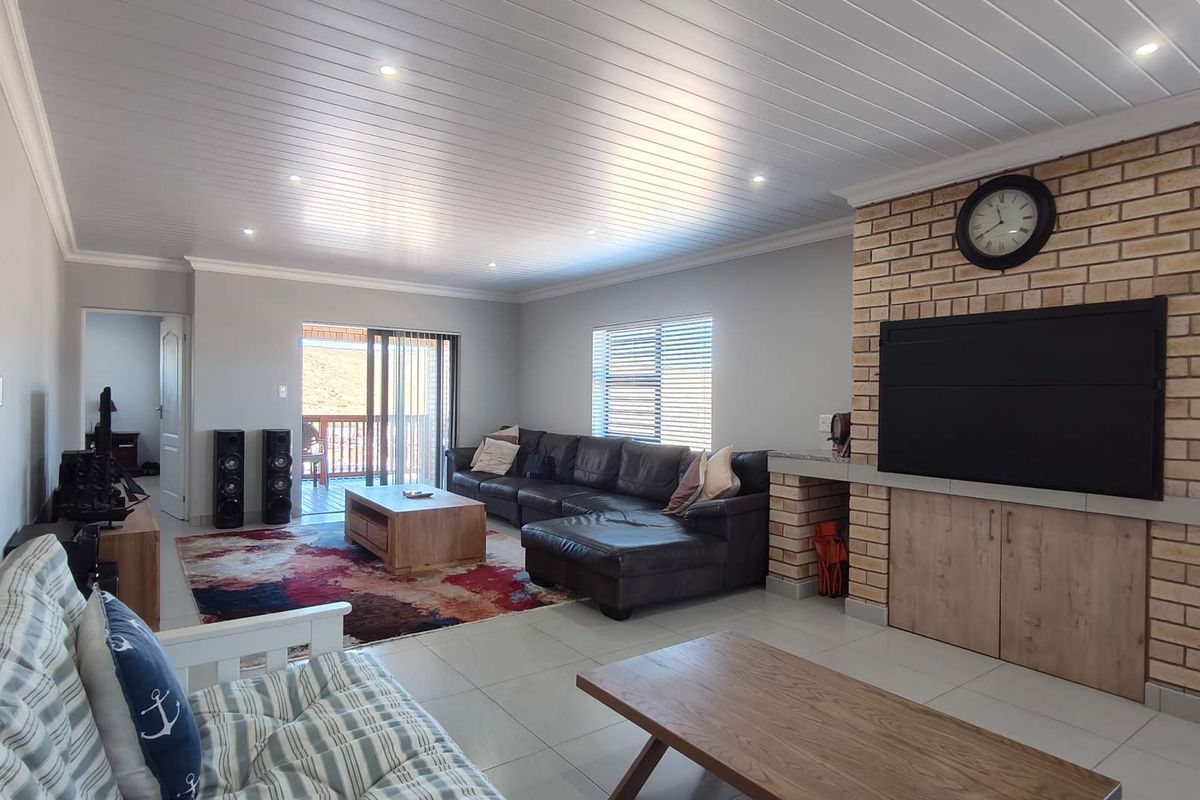 Spacious living room featuring a prominent brick fireplace, tiled flooring, recessed ceiling lighting, and sliding glass doors leading to an outdoor patio area.