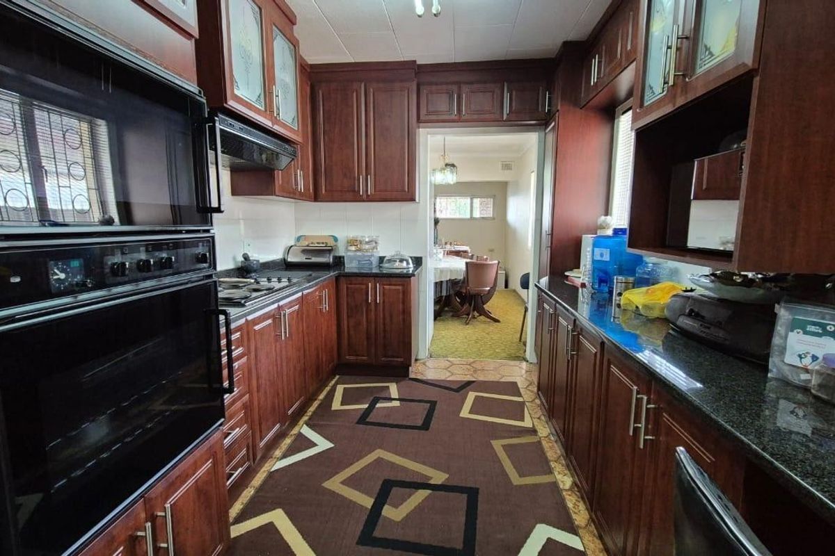 A functional kitchen featuring dark wood cabinetry, granite countertops, and integrated appliances, with a direct view into the adjacent dining area.