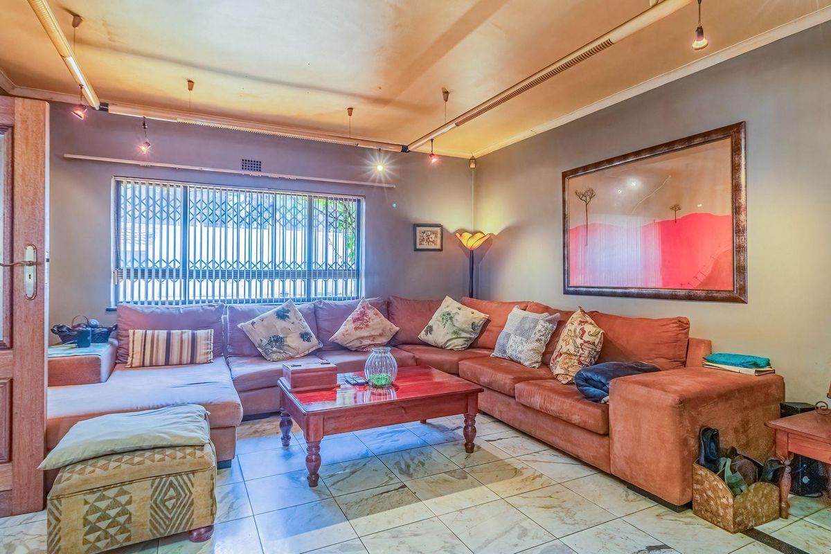 A living room featuring tiled flooring, track lighting, and a security gate on the window, offering a functional space with potential for modernization.