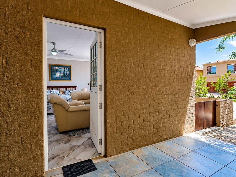 A covered patio area featuring textured brick walls and tiled flooring, providing direct access to the interior living space through a stable door.