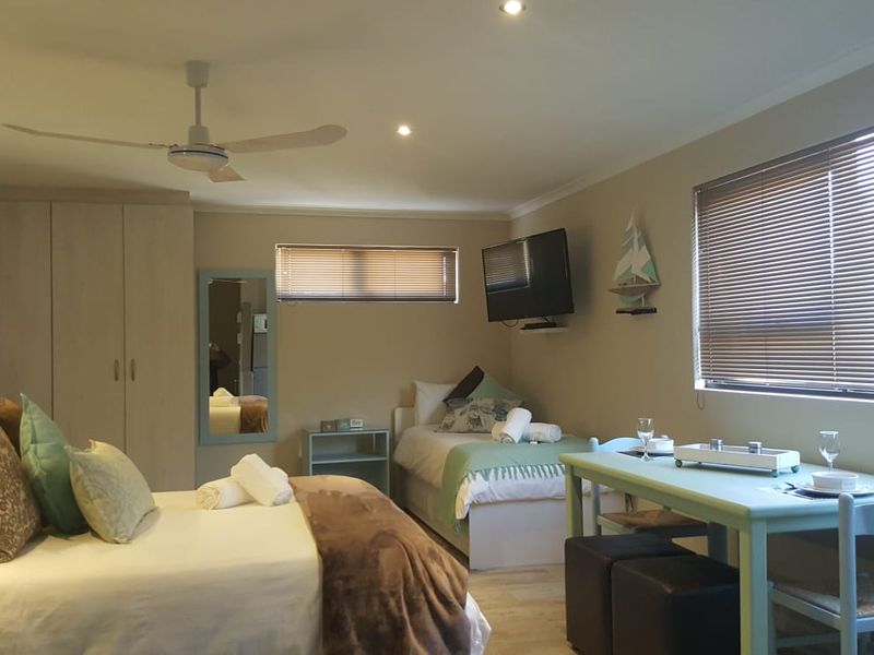Spacious bedroom featuring built-in cupboards, recessed downlighting, a ceiling fan, and large windows with venetian blinds, offering a functional and comfortable living space.