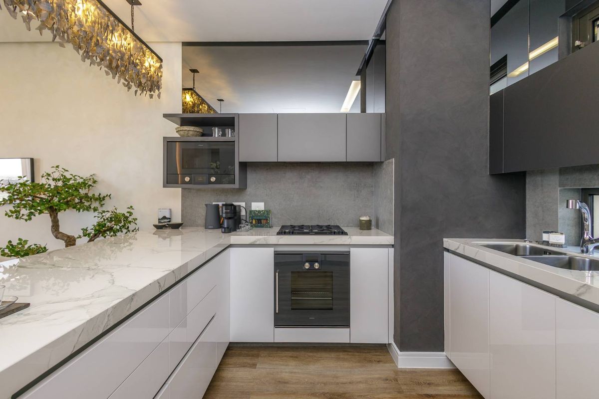 Modern kitchen featuring sleek white cabinetry, marble-look countertops, built-in oven, gas hob, and high-end finishes in a contemporary apartment setting.