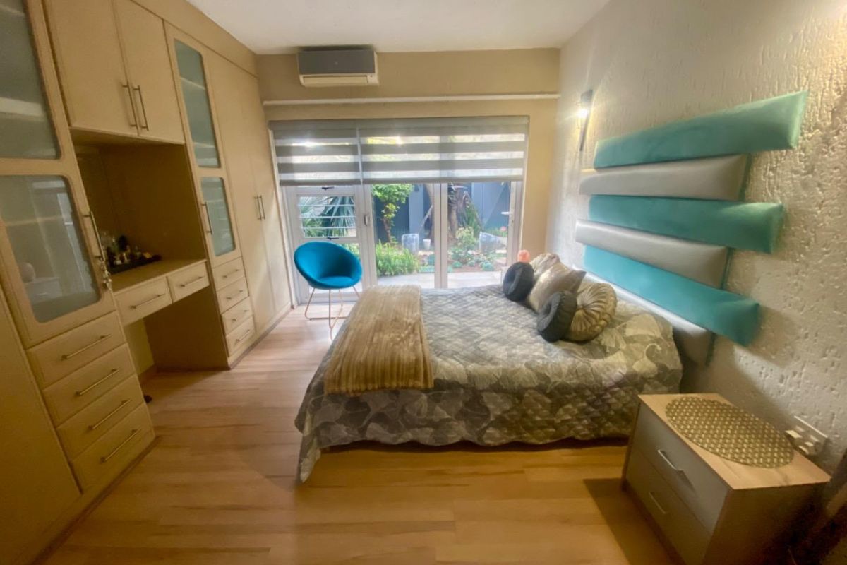 A bedroom featuring built-in wooden cabinetry, a wall-mounted air conditioning unit, and sliding glass doors providing access to an outdoor area.