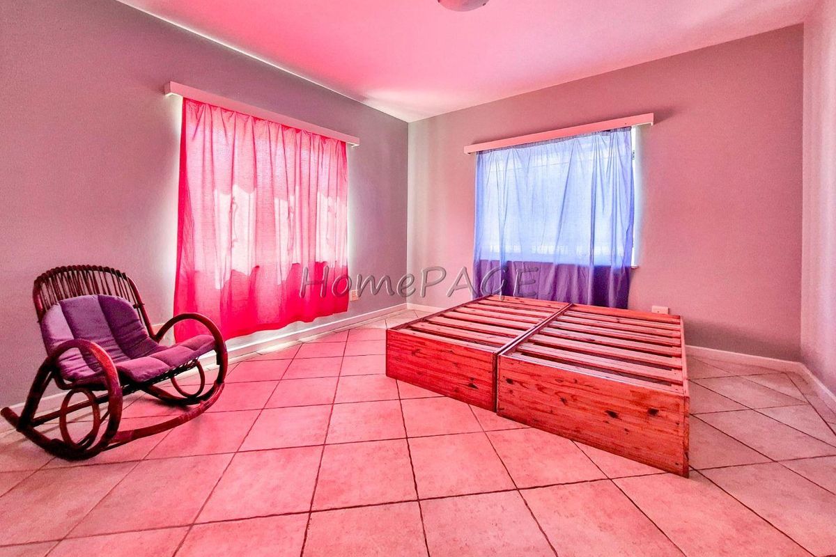 A spacious bedroom featuring tiled flooring and dual windows with curtain fixtures.