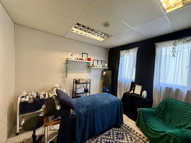 A functional office space featuring a suspended ceiling with recessed lighting and tiled flooring, currently utilized as a treatment room.