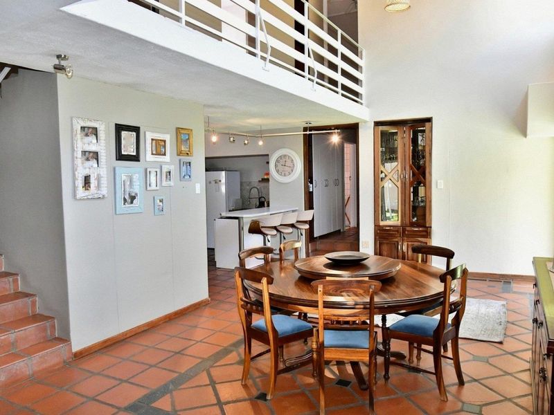Open-plan dining and kitchen area featuring terracotta tile flooring, a mezzanine level, and a built-in display cabinet.