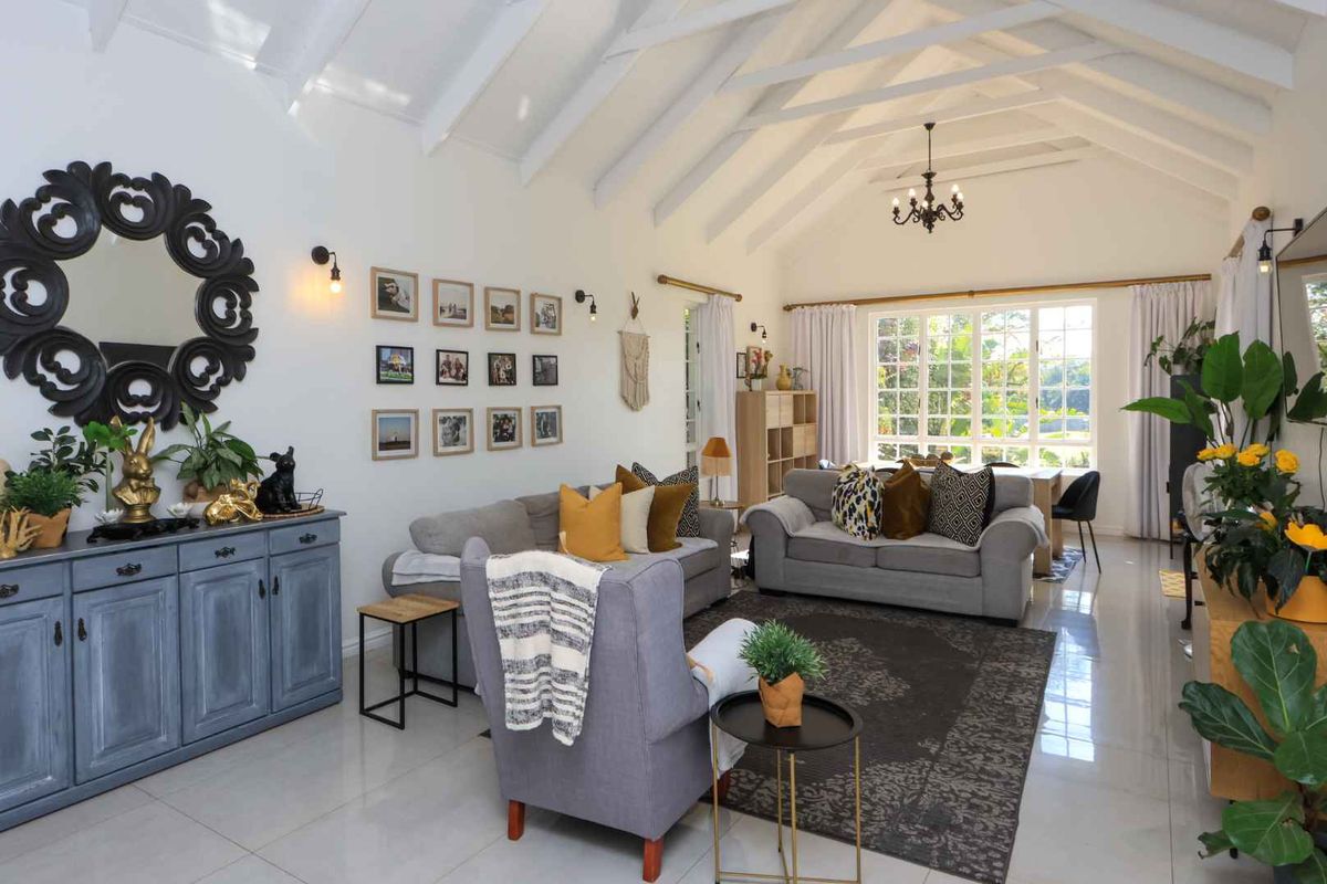 Spacious living room featuring a high vaulted ceiling with exposed rafters, polished tiled flooring, and large windows providing ample natural light.