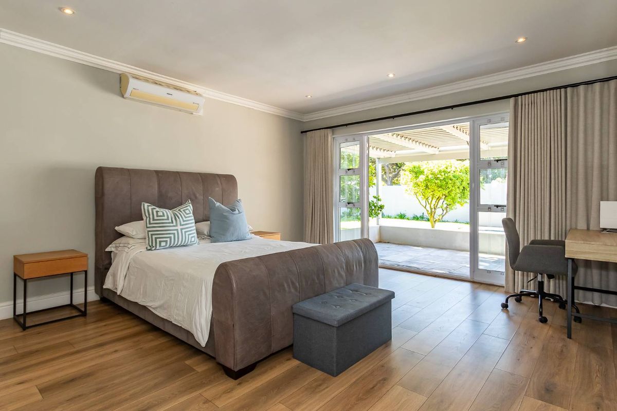 Spacious bedroom featuring wood-look flooring, recessed lighting, crown molding, and a wall-mounted air conditioning unit, with direct access to a private patio.