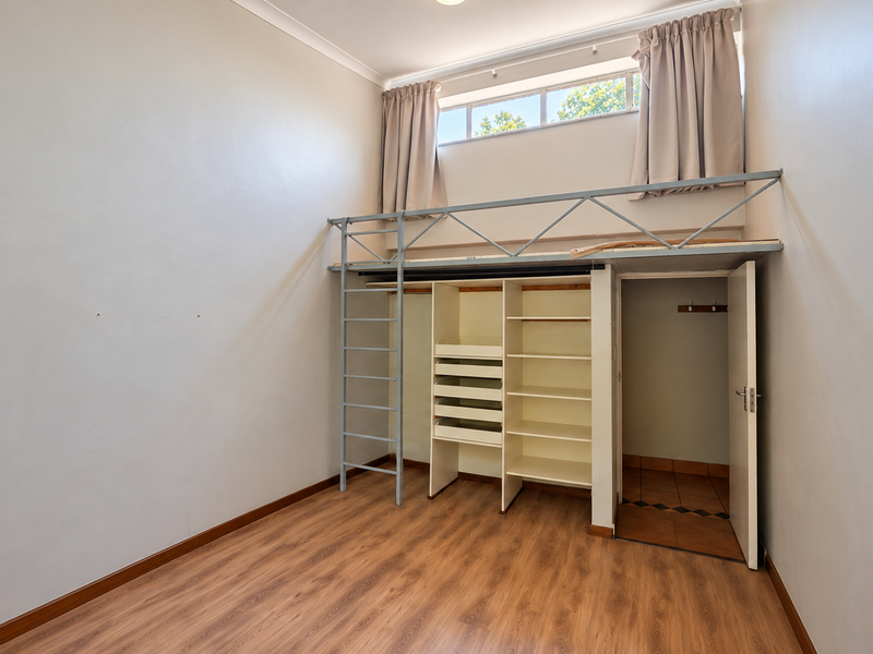 Bedroom featuring a built-in mezzanine loft structure with integrated shelving, ladder access, and laminate flooring.