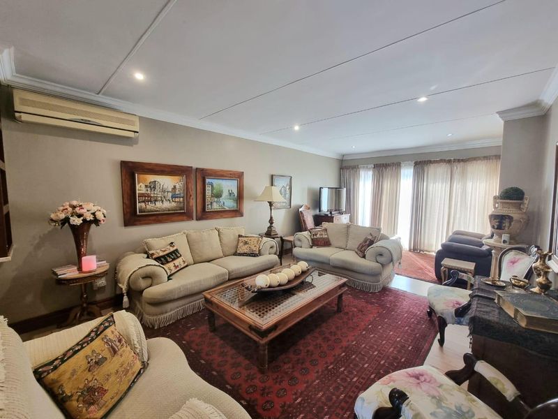 A spacious living room featuring recessed downlights, a wall-mounted air conditioning unit, and large sliding glass doors providing access to the exterior.