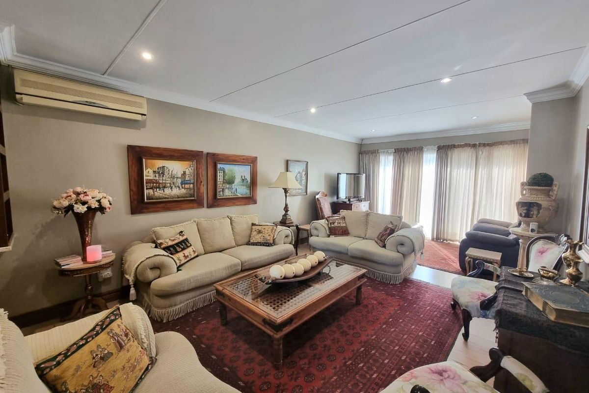 A spacious living room featuring recessed downlights, a wall-mounted air conditioning unit, and large sliding glass doors providing access to the exterior.