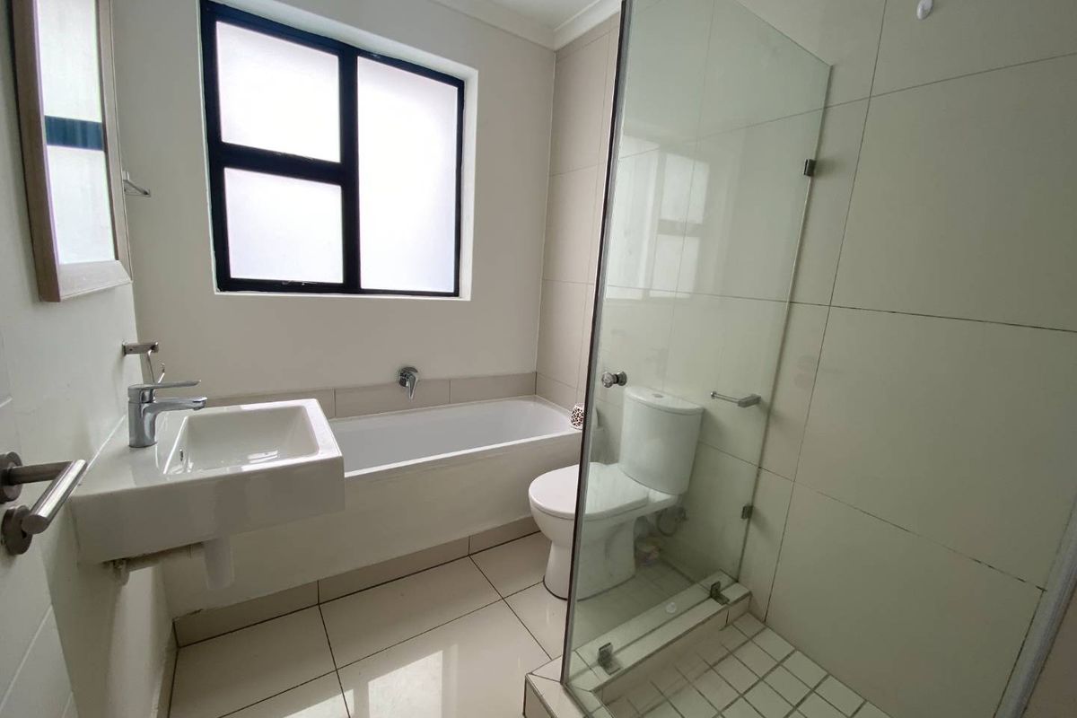 Modern bathroom featuring a wall-mounted basin, a bathtub, and a separate glass-enclosed shower with tiled flooring and walls.