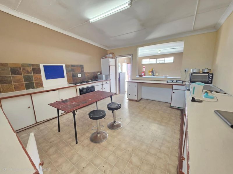 A dated kitchen featuring built-in cabinetry, a tiled splashback, and a built-in oven, offering significant potential for modernization and renovation.