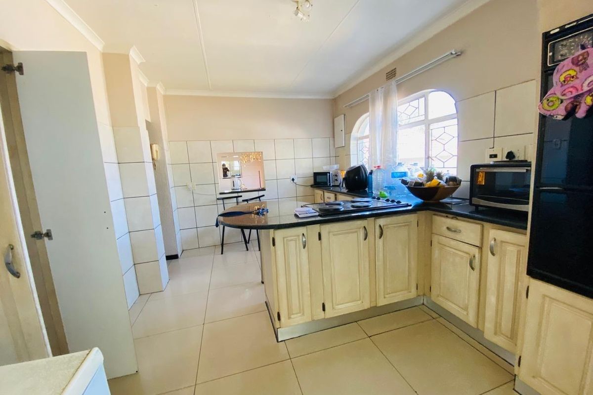 A functional kitchen featuring built-in cabinetry, granite countertops, a hob, and tiled finishes, offering a practical layout with potential for modern updates.
