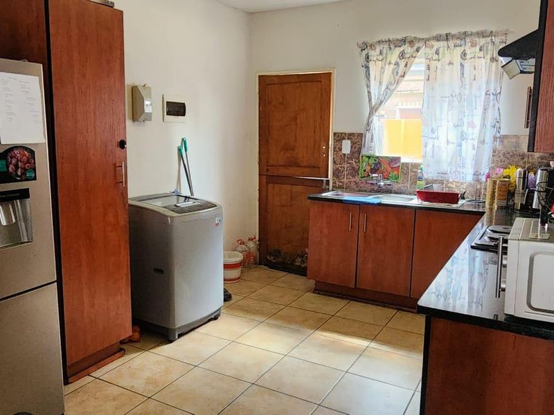 Functional kitchen featuring built-in wooden cabinetry, tiled flooring, a double sink, and a built-in hob with an extractor fan.