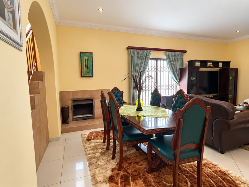 Spacious living area featuring tiled flooring, a built-in fireplace, and an arched entryway leading to the staircase.