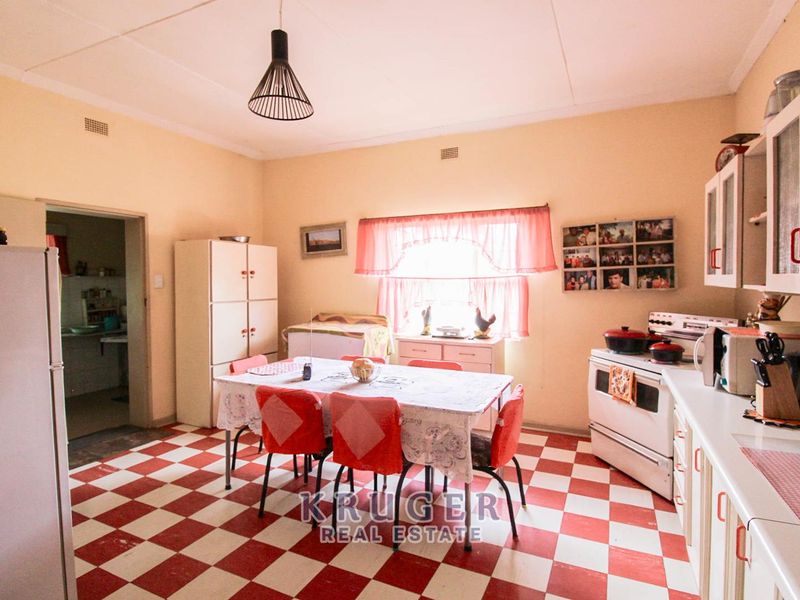 A spacious, dated kitchen featuring classic checkerboard tiled flooring, built-in cabinetry, and a freestanding stove, offering significant potential for a modern renovation.