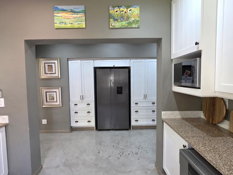 A functional kitchen featuring white built-in cabinetry, granite countertops, a built-in microwave, and polished concrete flooring.