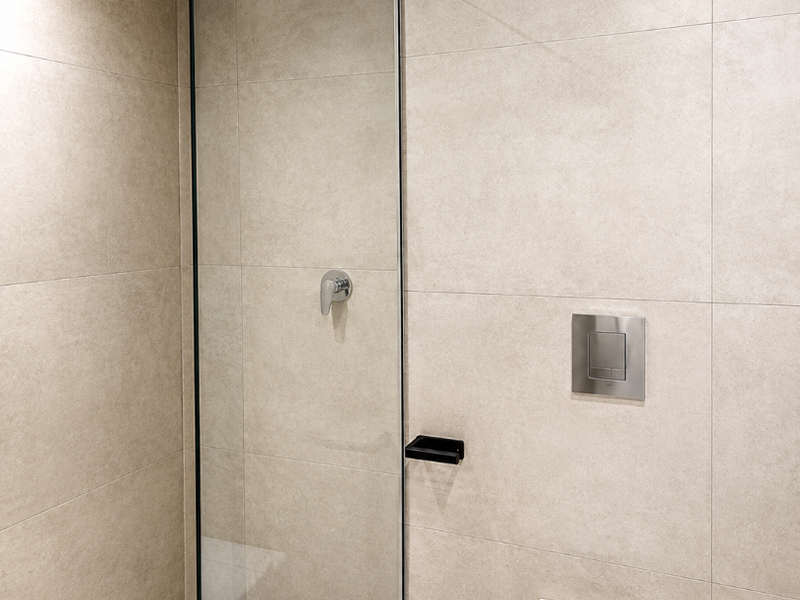 Modern bathroom featuring a glass-enclosed walk-in shower with a rain shower head and a wall-mounted toilet with a sleek flush plate.