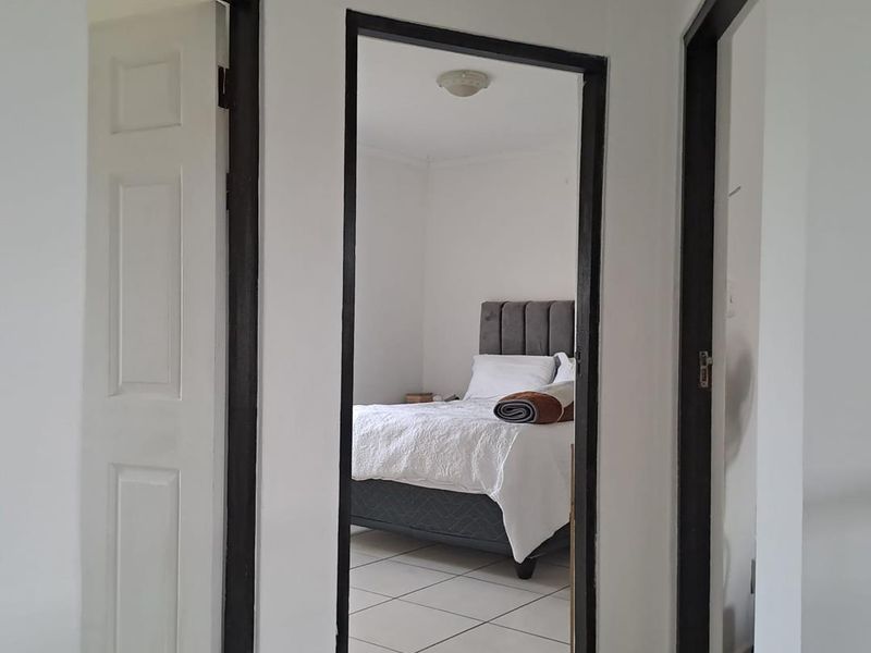 A view from the hallway looking into a bedroom featuring tiled flooring and contrasting dark door frames.