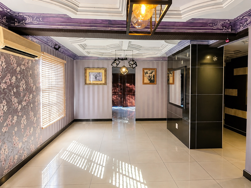 Spacious living area featuring ornate coffered ceilings, polished porcelain floor tiles, split-system air conditioning, and decorative wallpaper finishes.