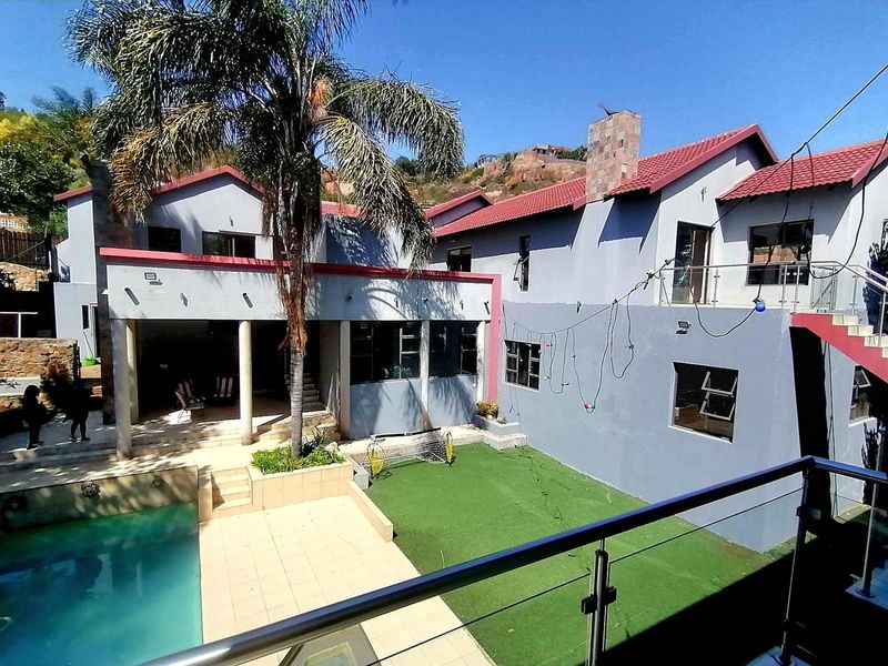 Rear view of the property featuring a swimming pool, tiled patio area, artificial lawn, and an external staircase with glass balustrades.