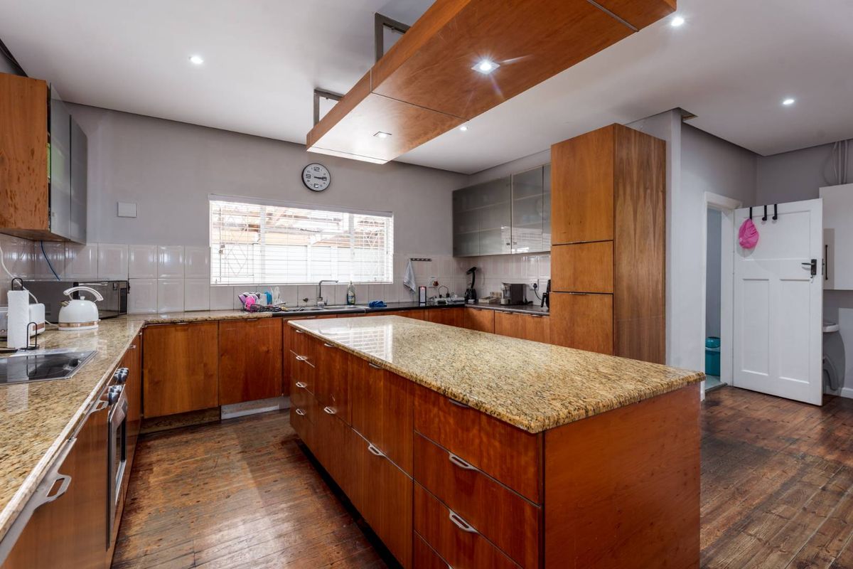Spacious kitchen featuring wooden cabinetry, granite countertops, a central island, built-in oven, and hardwood flooring, offering a functional layout with ample storage space.