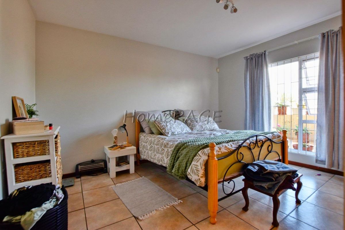 A bedroom featuring tiled flooring and a sliding door leading to a balcony, providing natural light and access to outdoor space.