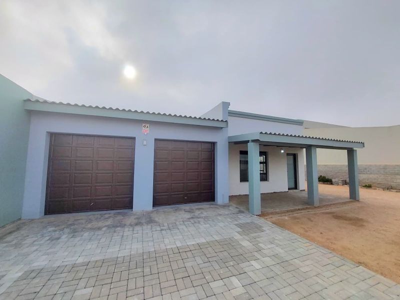 Front exterior view featuring a double garage, paved driveway, and a covered patio area with potential for landscaping.