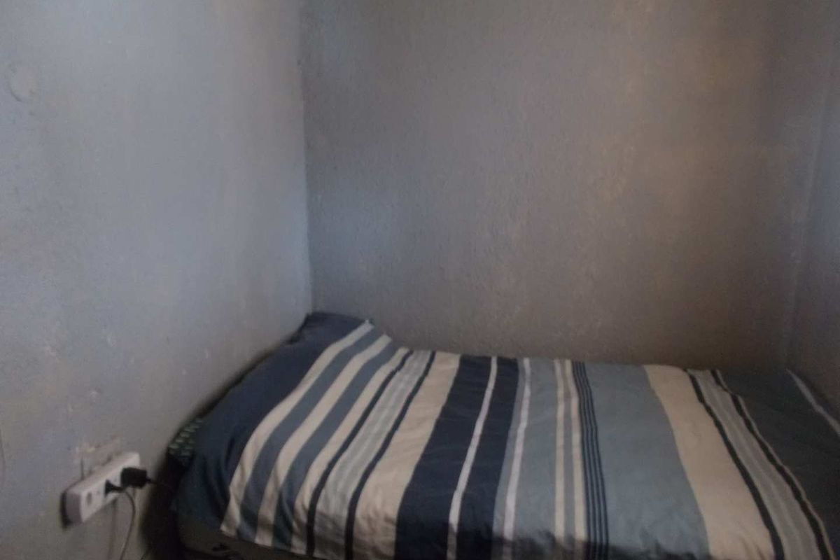 A small bedroom featuring plain walls and a single electrical outlet, requiring cosmetic updates to improve the overall finish and appeal.