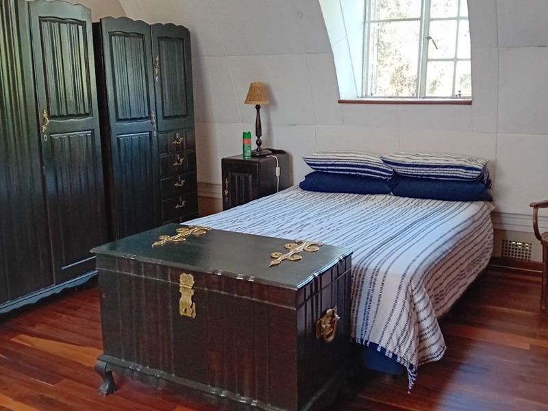 A bedroom featuring hardwood flooring, a sloped ceiling, and a dormer window, providing a cozy and traditional atmosphere.
