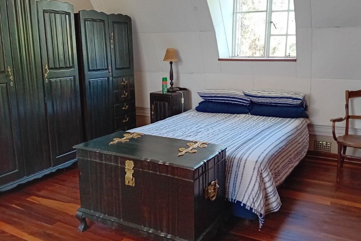 A bedroom featuring hardwood flooring, a sloped ceiling, and a dormer window, providing a cozy and traditional atmosphere.