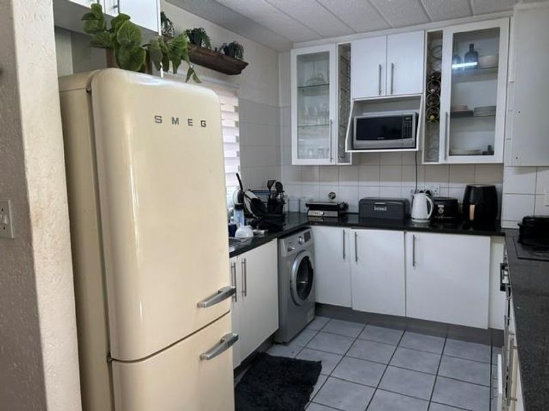 A functional kitchen featuring white cabinetry, granite countertops, tiled flooring, and integrated microwave, offering a clean and practical workspace.