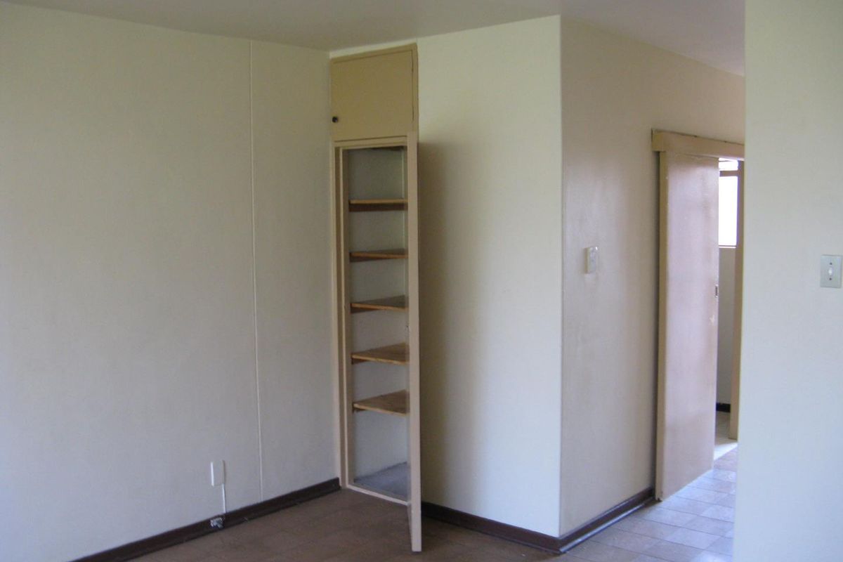 An empty interior space featuring built-in shelving, tiled flooring, and a sliding door leading to an adjacent area.