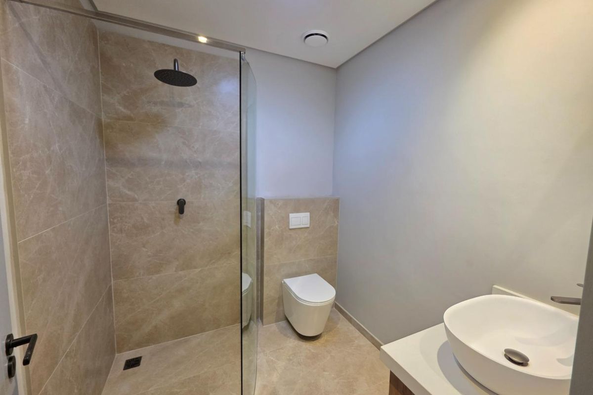 Modern bathroom featuring a walk-in shower with glass screen, wall-hung toilet with concealed cistern, and a contemporary vessel sink vanity.