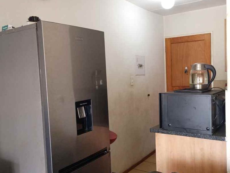 A compact kitchen area featuring basic cabinetry and laminate countertops, showing signs of wear on the walls and flooring.