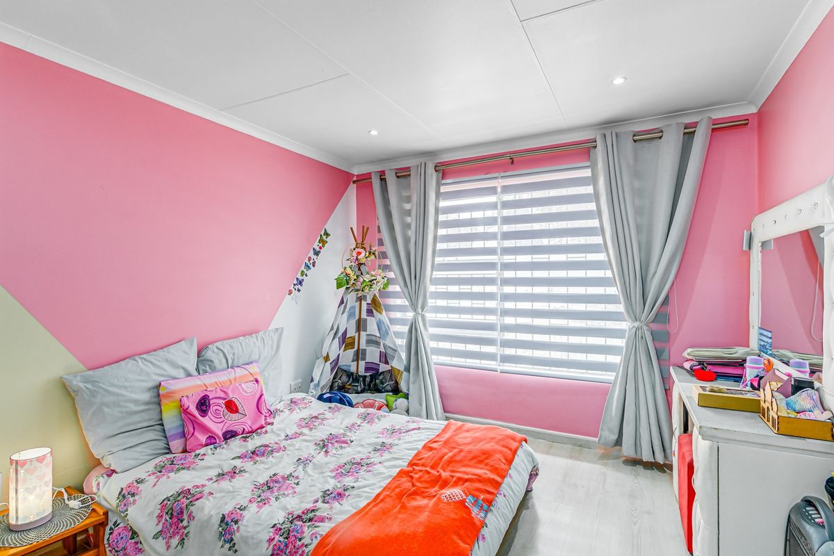A bedroom featuring laminate flooring, recessed ceiling lighting, and window blinds, currently decorated with vibrant pink wall paint.